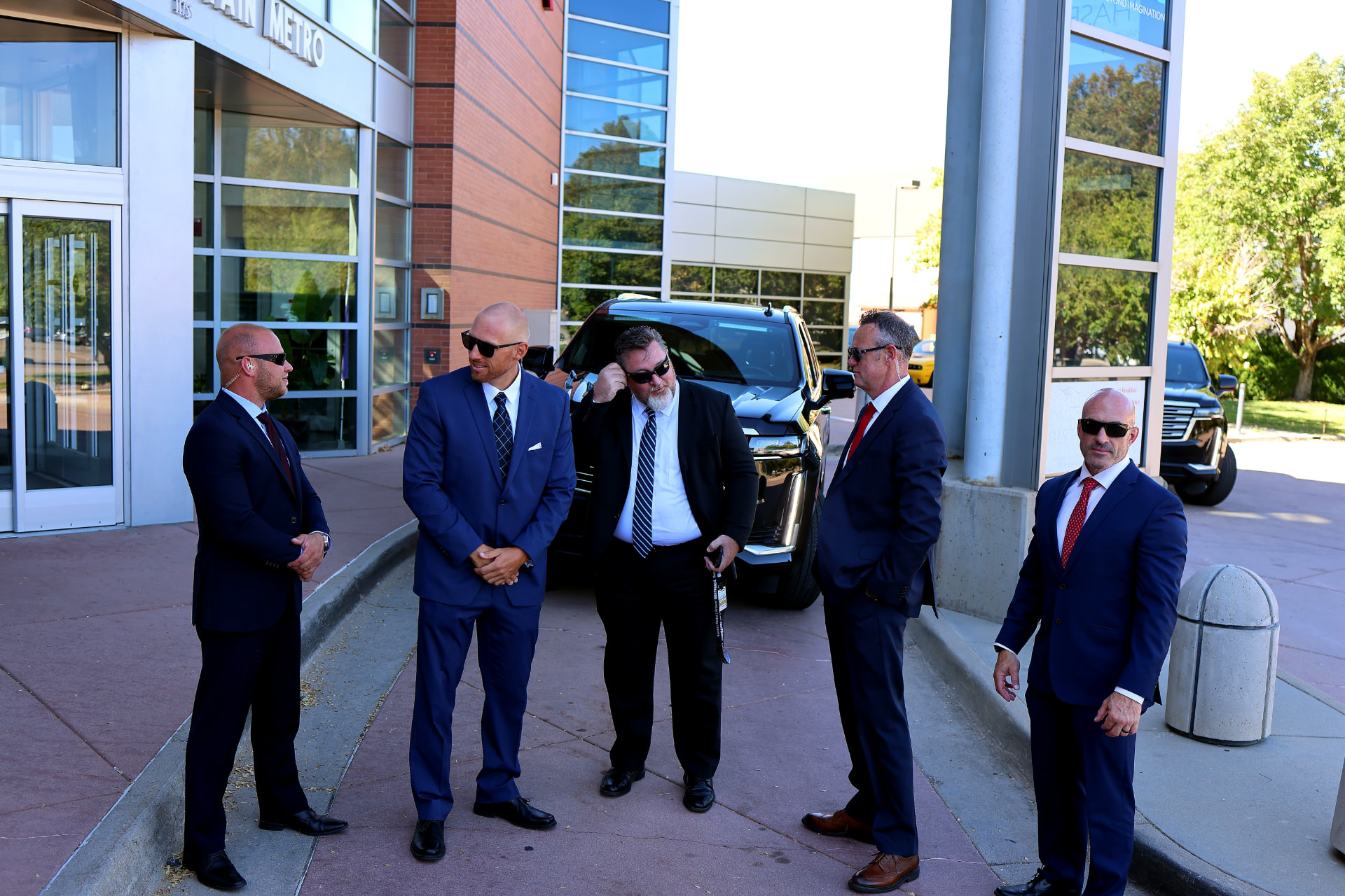 AMERINE team members in business attire beside executive vehicles.